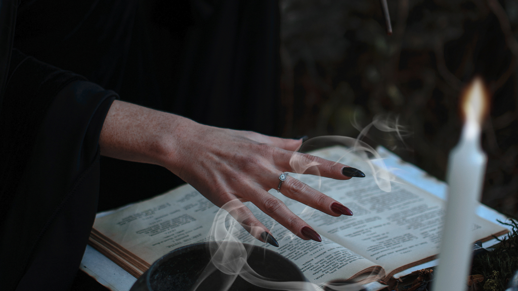mano de una bruja encima de un libro